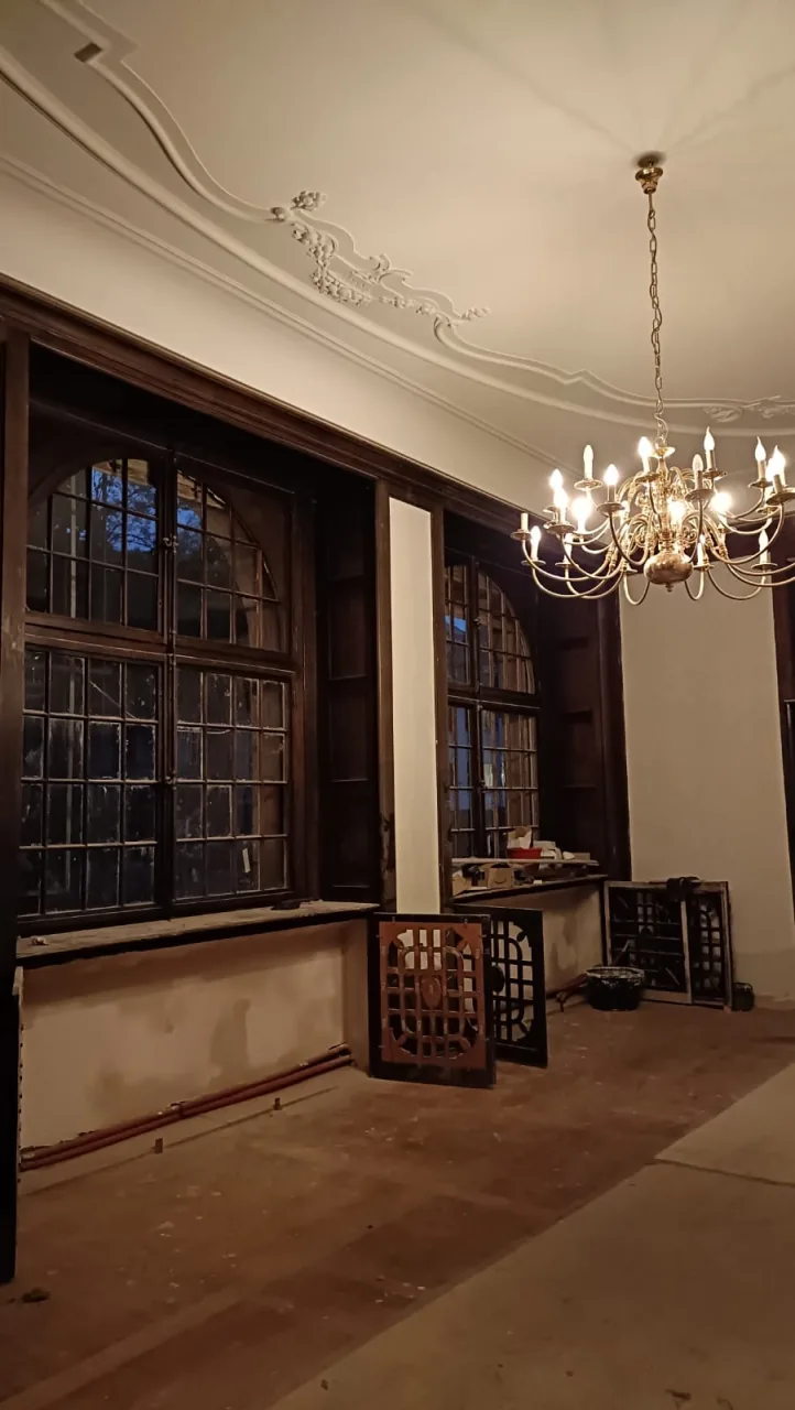 Ruimte in renovatie met oude vensters en stucwerk aan het plafond